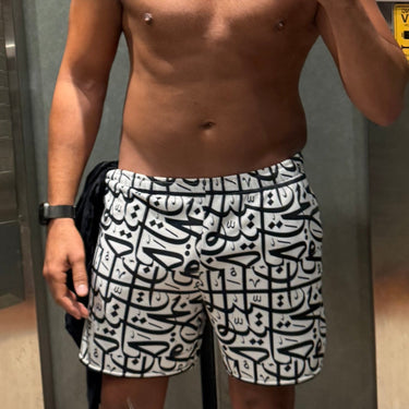 Person taking a mirror selfie in an elevator wearing patterned shorts.