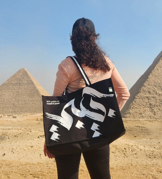 A person carrying a Habibi Please statement tote at the pyramids in Egypt