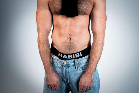 English HABIBI jockstrap waistband styled with blue jeans and a black tie; jeans and tie not included