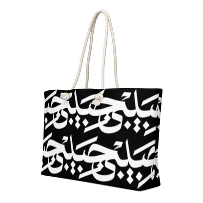 Black-and-white Habibi calligraphy tote with cream rope handles, left angled view