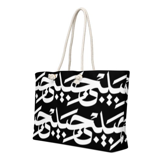 Black-and-white Habibi calligraphy tote with cream rope handles, left angled view