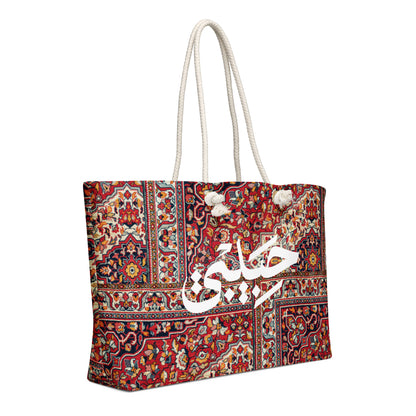 Red rug-print Habibi weekender bag with cream rope handles, right angled view